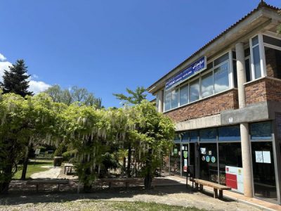 Vista exterior del Centro de Iniciativas Municipales de Collado Villalba en un día soleado. El edificio de ladrillo cuenta con grandes ventanales y está rodeado de vegetación.