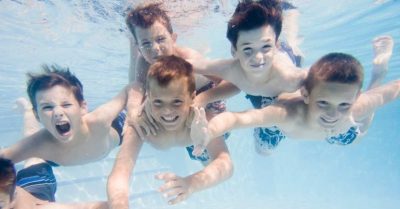 Niños buceando con los ojos abiertos en la piscina