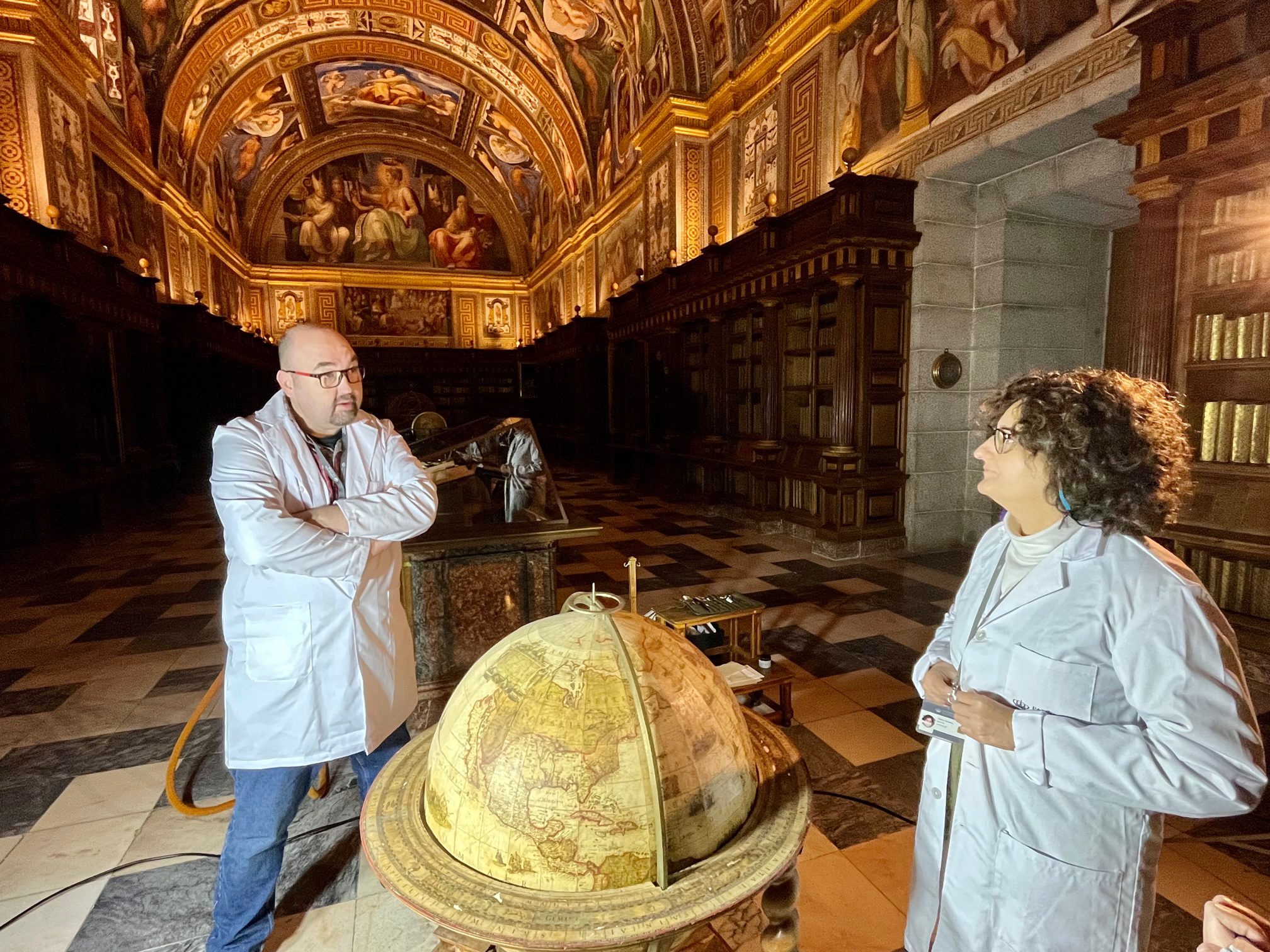 Teresa Martín y Rubén Sánchez, ante una de las esferas de la Biblioteca del Monasterio en las que han trabajado las últimas semanas / Fotografía: E. P.