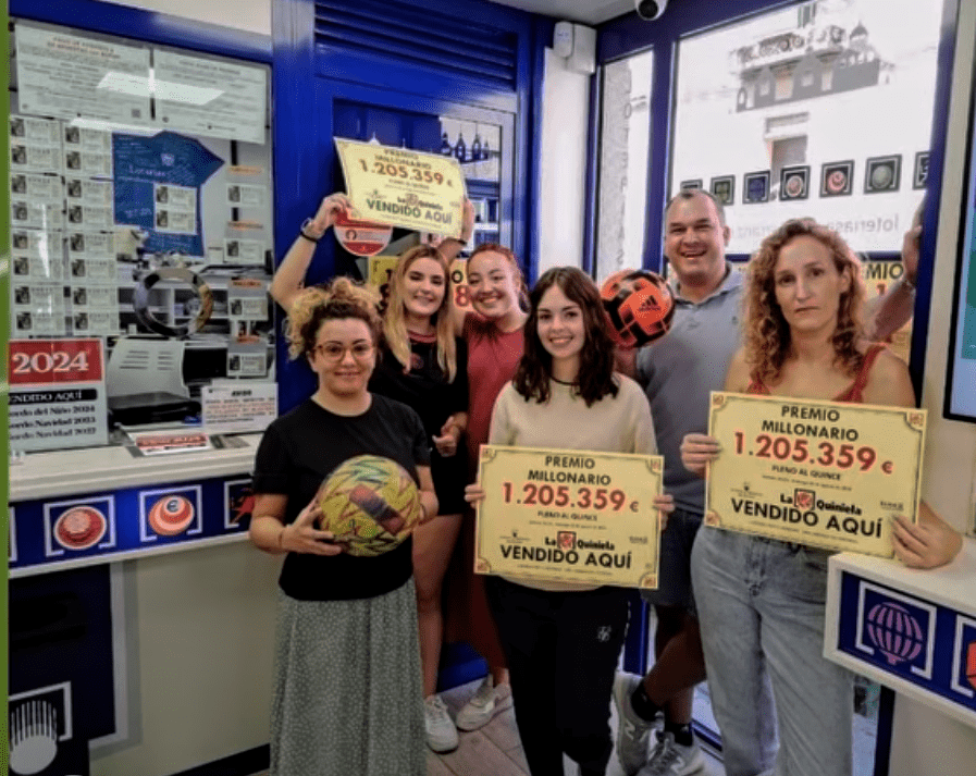 Trabajadores de la Administración de Loterías Pepito Herranz, con el cartel del premio de 1,2 millones de euros en La Quiniela