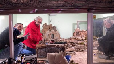 Voluntarios y miembros de la Asociación de Belenistas de El Escorial ultiman el montaje del Belén tradicional en la Plaza de España