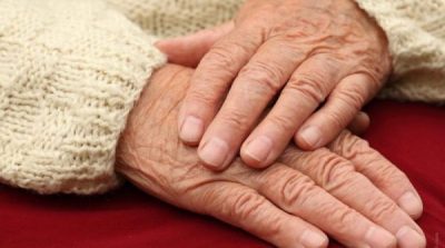 Primer plano de las manos entrelazadas de una persona mayor. Las manos muestran arrugas y signos de la edad. 