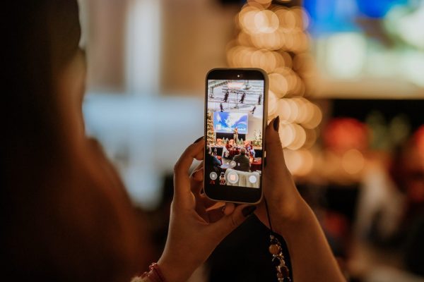 Manos sujetando un móvil, tomando una foto del escenario de la presentación de la campaña de Navidad de Las Rozas.