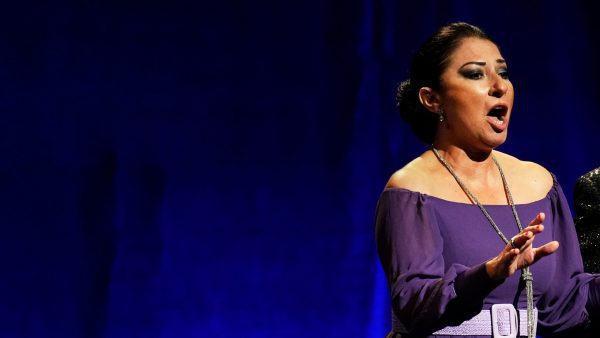 Montserrat Martí, hija de la legendaria soprano Montserrat Caballé en el escenario cantantando, detrás una cortina azul