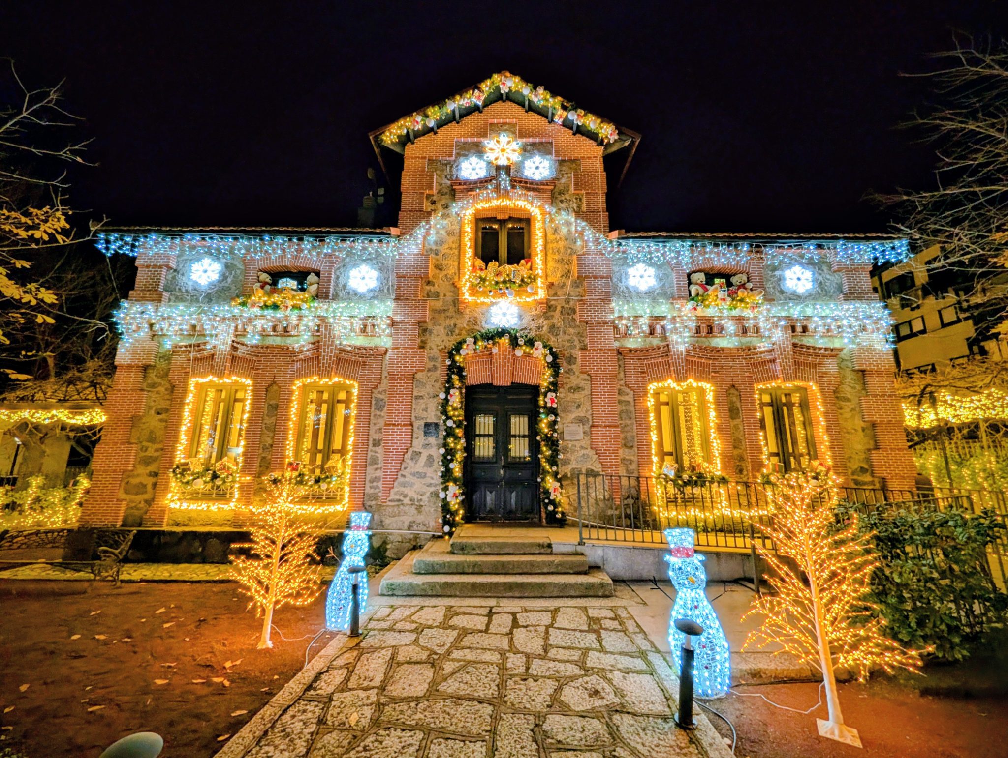 Vista central de la Casita y el Jardín de la Navidad de El Escorial totalmente iluminados de noche.