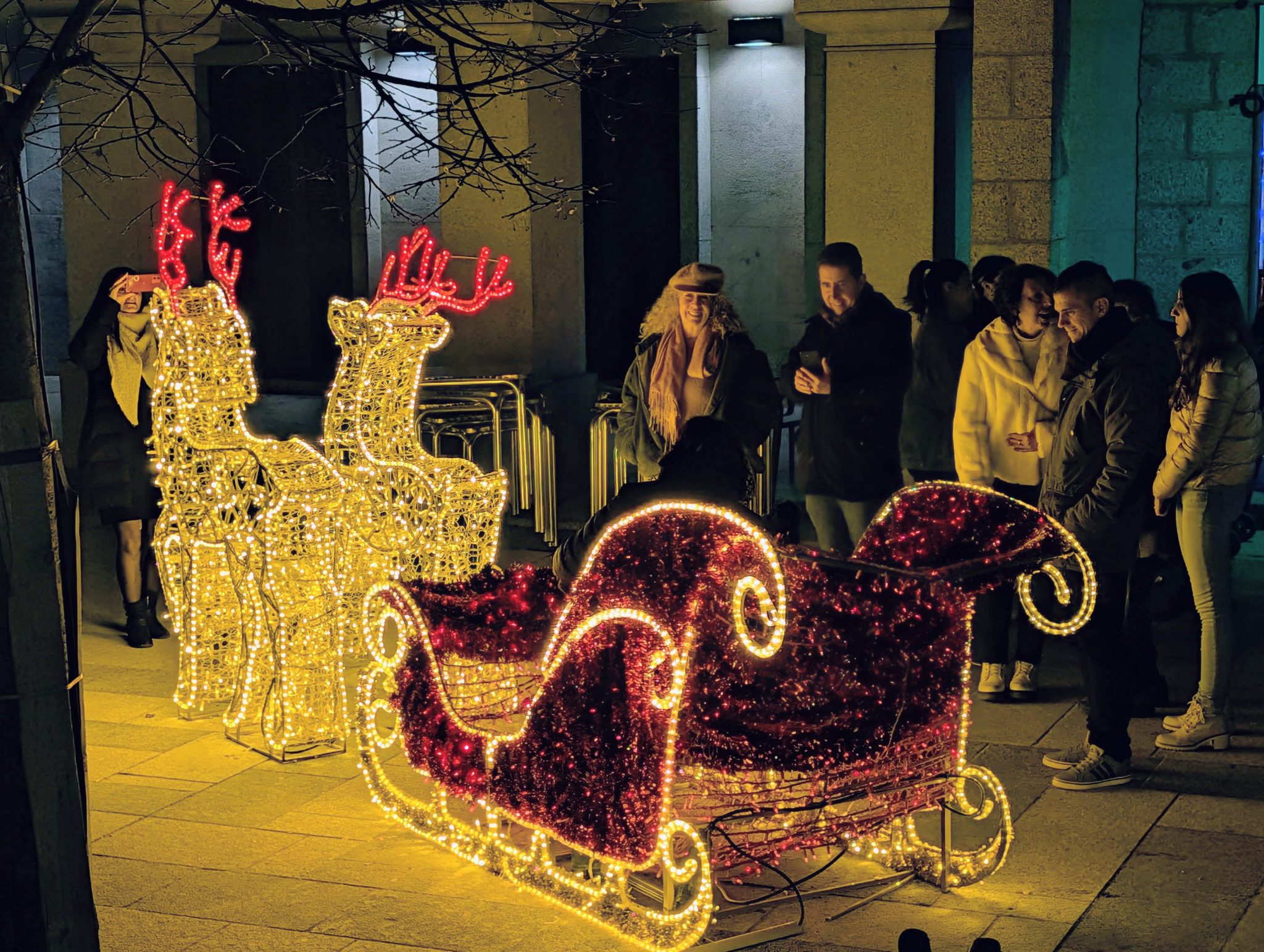 Trineo y renos luminosos de Papá Noel instalados en la Plaza de España, con gente alrededor.