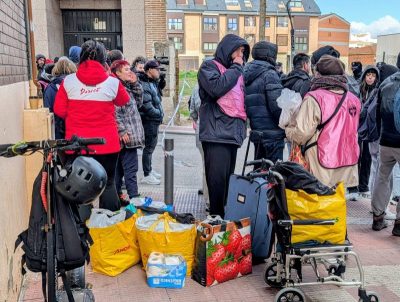 Un grupo de personas, varias de ellas con chalecos rosas, se congregan en una calle de Collado Villalba.