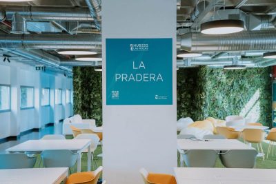 Primer plano de una columna blanca con un cartel azul cuadrado que dice "HUB232 LAS ROZAS" y "LA PRADERA",