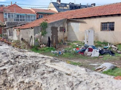 Imagen de la antigua lechería- vaquería de la calle Asturias con el tejado roto, ropa y enseres abandonados en el exterior.