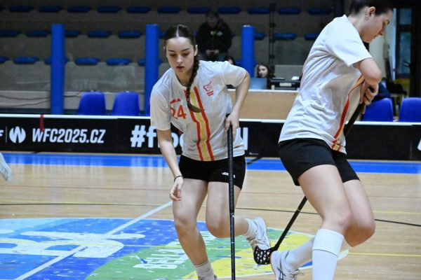 Dos jugadoras de floorball en plena acción durante un partido en una pista cubierta.