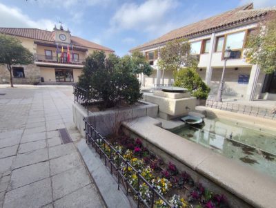 Plaza pública de Torrelodones con una fuente central y edificios municipales al fondo.