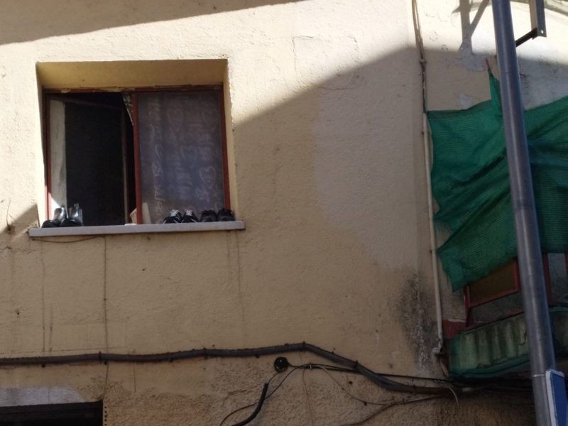 Primer plano de una ventana del edificio con varios pares de zapatos en el alféizar.