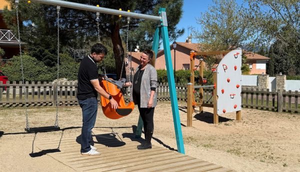 El concejal José María Escudero, y Carla Greciano supervisan un nuevo columpio adaptado en un parque infantil al aire libre.