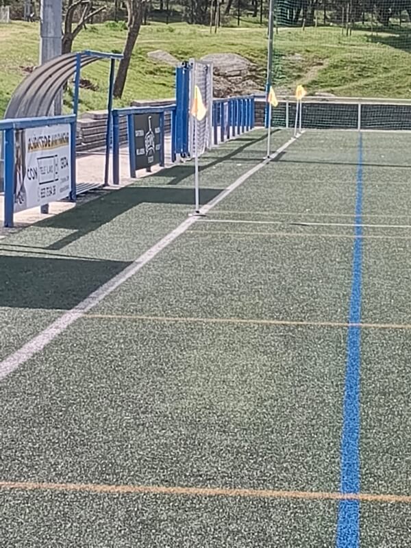 Primer plano de banderines amarillos de señalización instalados sobre el césped del campo de la Ciudad Deportiva.
