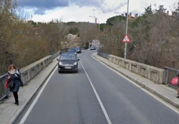 Vista actual del Puente de La Navata en Galapagar, con tráfico de vehículos y peatones transitando por aceras estrechas.