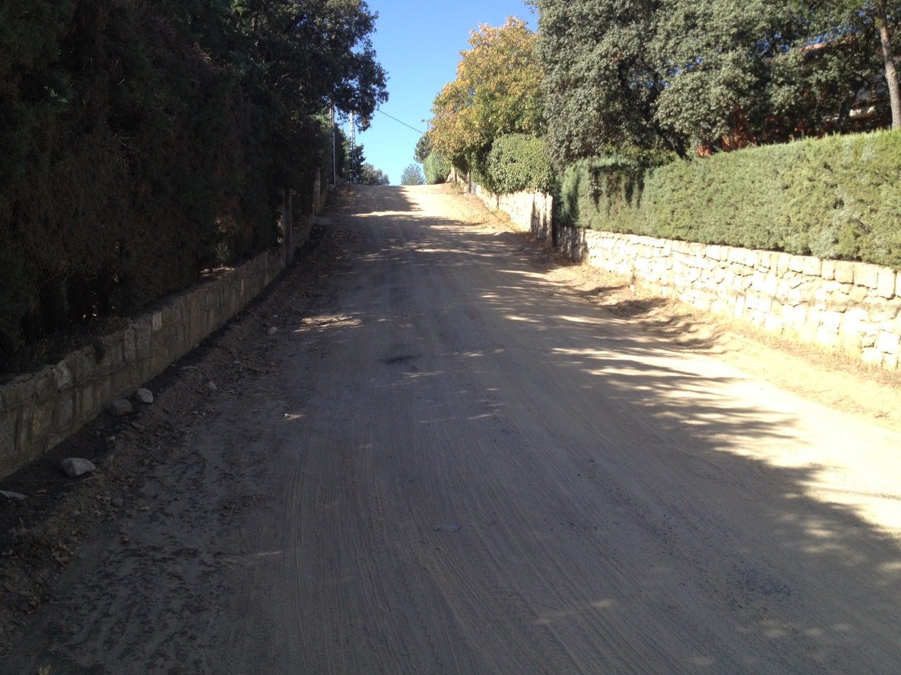 Vista en perspectiva de una calle de tierra con firme irregular y vegetación a los lados en la zona de Montencinar.