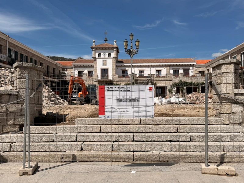 Zona de obras vallada con maquinaria pesada frente a un edificio institucional y un cartel del "Plan Integral de Embellecimiento".
