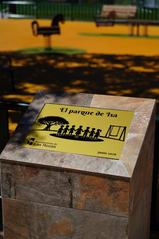 Primer plano de una placa dorada sobre un monolito de piedra con el texto "El parque de Isa", "junio 2026" y el logo del Ayuntamiento de Las Rozas.