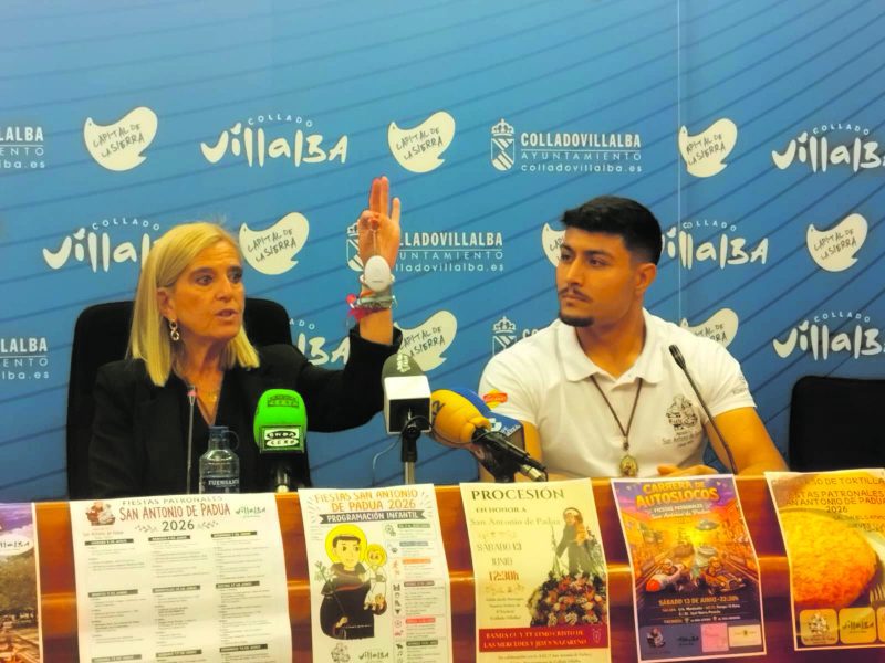 La alcaldesa Mariola Vargas muestra un objeto blanco con la mano izquierda alzada junto a un joven en la mesa.