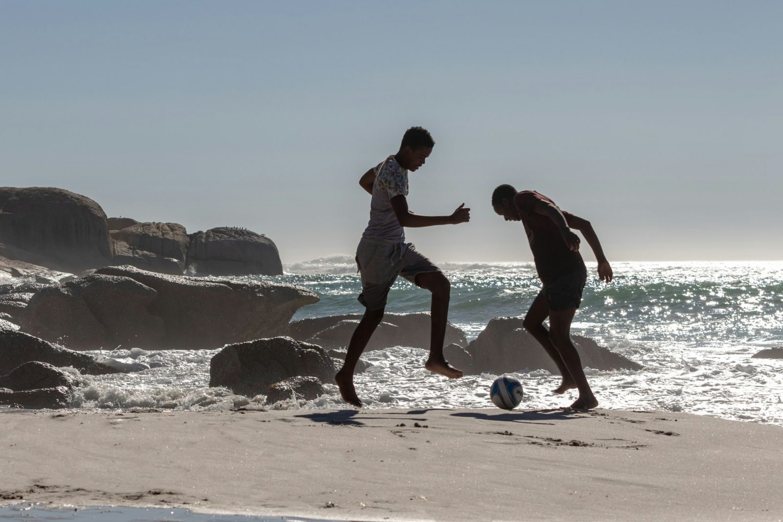 Dos hombres jugando al fútbol cerca del mar