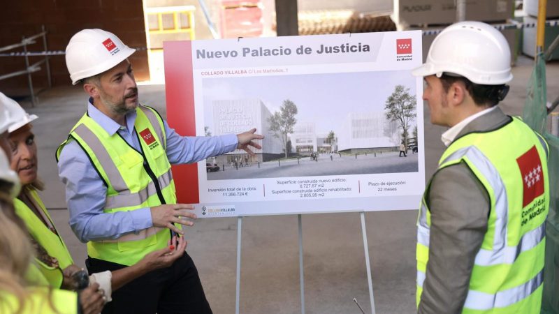 Un representante explica el cartel del proyecto del Nuevo Palacio de Justicia a otros asistentes en la obra.