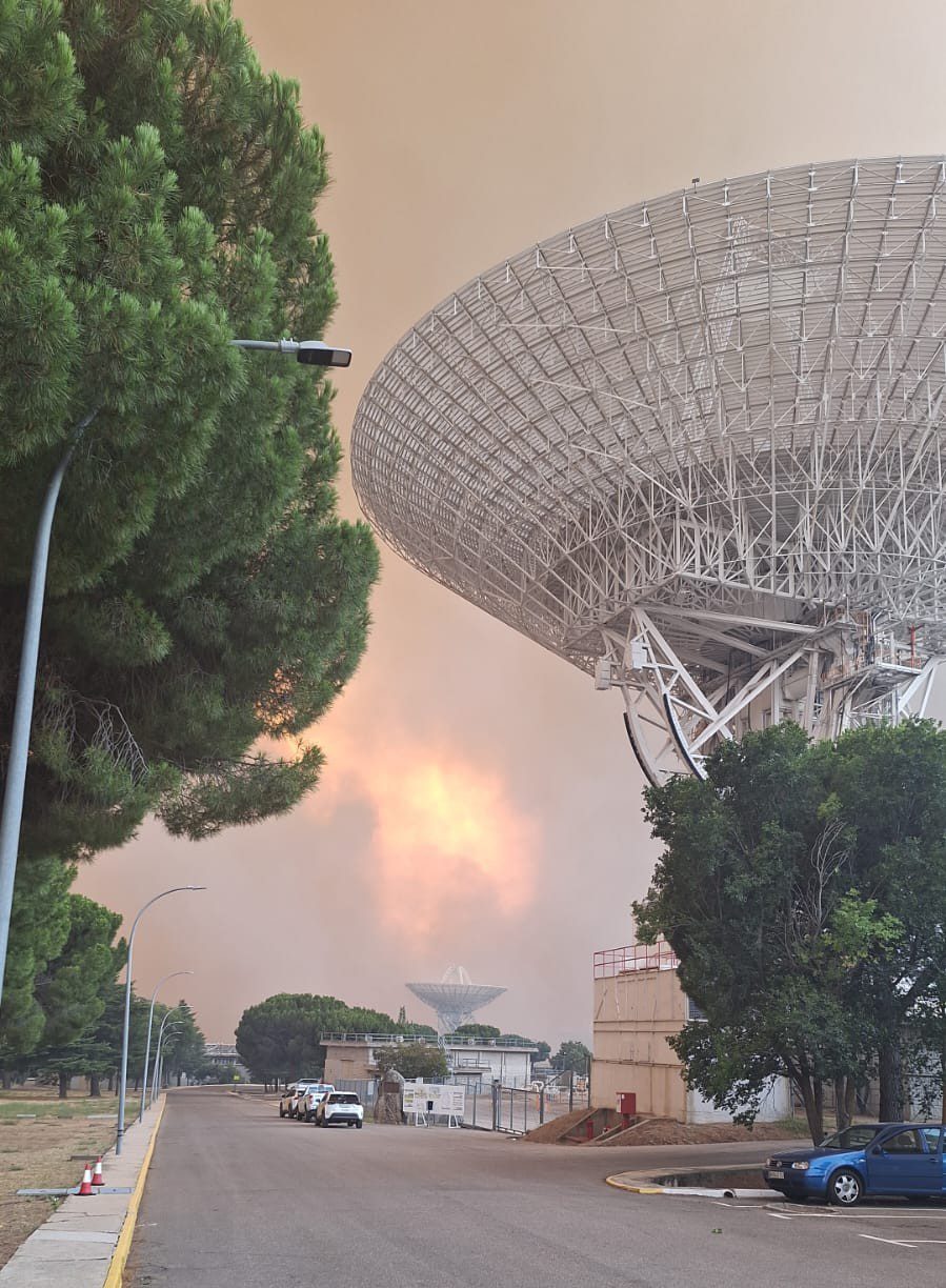 Antena de comunicaciones con humo y llamas del incendio forestal al fondo.