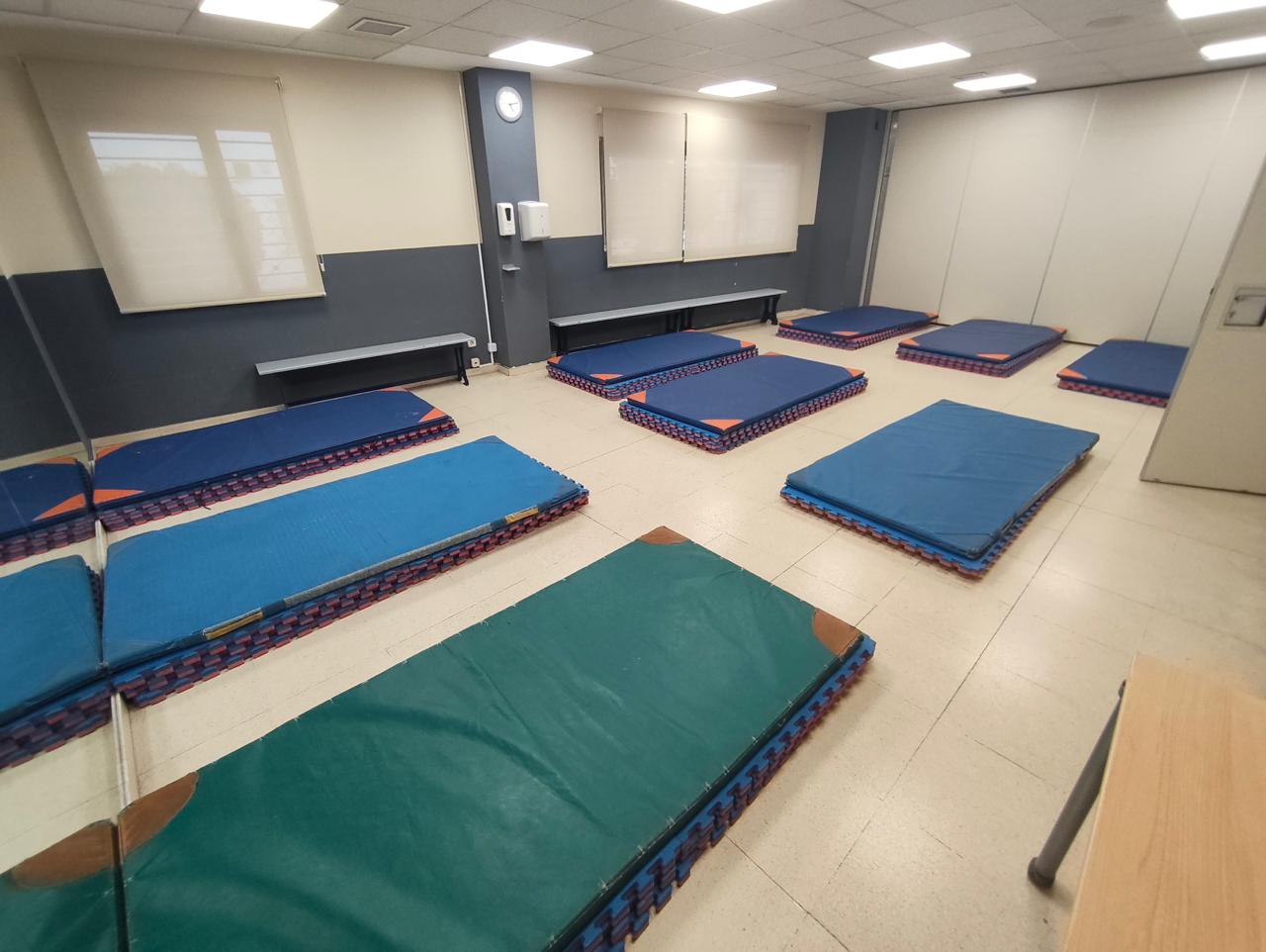Sala con colchonetas distribuidas para el descanso en el espacio habilitado para personas mayores evacuadas.