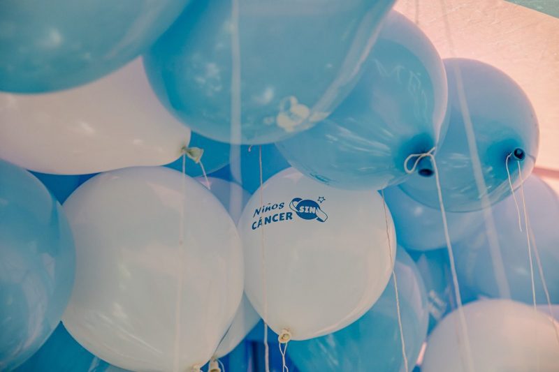 Primer plano de globos azules y blancos inflados, uno de ellos con el logotipo de la iniciativa Niños Sin Cáncer.