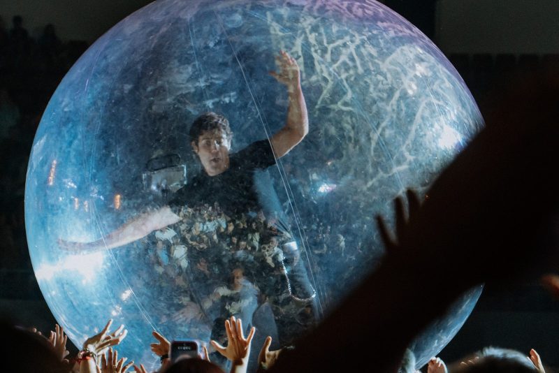 Un artista en el interior de una gran esfera transparente flotando sobre el público.