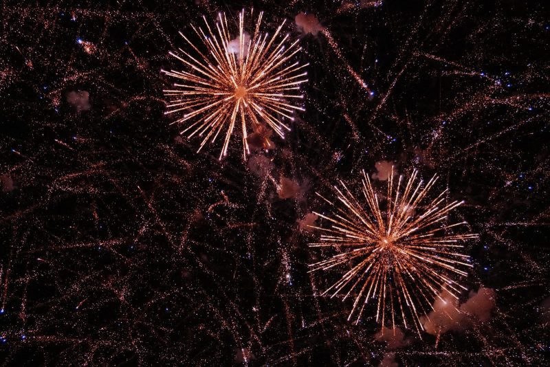 Espectáculo de fuegos artificiales con destellos luminosos dorados sobre el cielo oscuro.