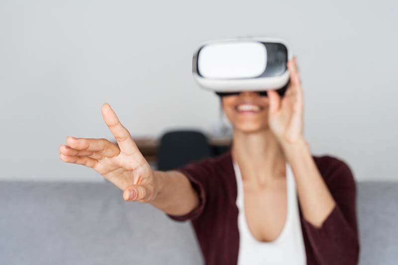 Una persona sonriendo mientras utiliza gafas de realidad virtual y estira el brazo hacia adelante.