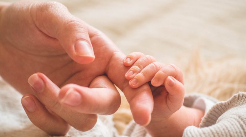 Female hand holding her newborn baby hand. Mom with her child. Maternity, family, birth concept. Copy space for your text.