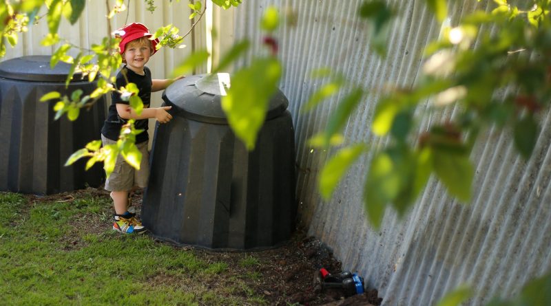 A kid trying to open a composter in the garden