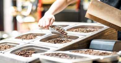 Filling paper bag with coffee beans from the metal trays for selling in the store