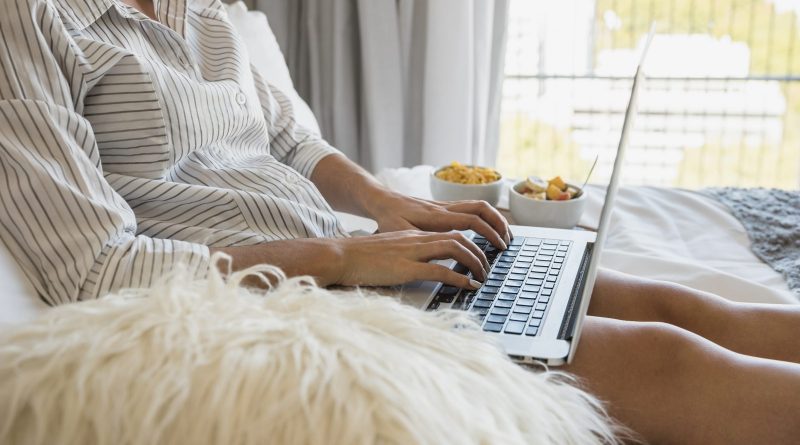 young-woman-sitting-bed-using-laptop-with-healthy-breakfast