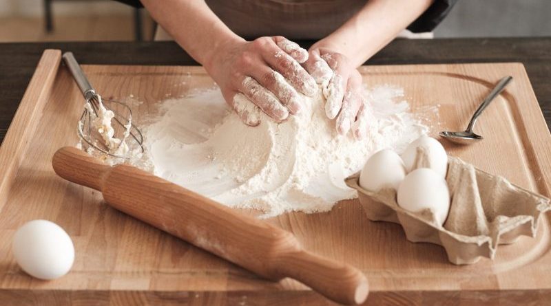 Close-up of unrecognizable woman touching hill of flour while kneading dough with hands