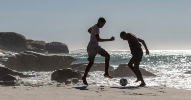 Dos hombres jugando al fútbol cerca del mar