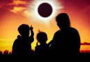 Natural phenomenon. Silhouette back view of family sitting and relaxing together. Boy point to solar eclipse on gold sky background. Happy family spending time together. Outdoor.