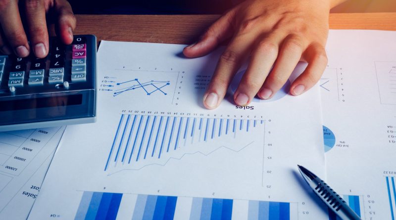 Selective focus hand asian business man is calculating finance and accounting with growth up paper chart on wood table in home office.Pen calculator graph document on desk.economy,saving,financial.