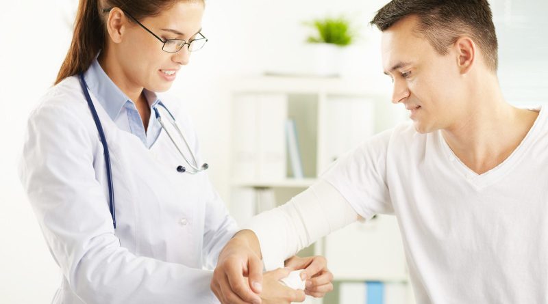 Woman doctor bandaging hand of male patient